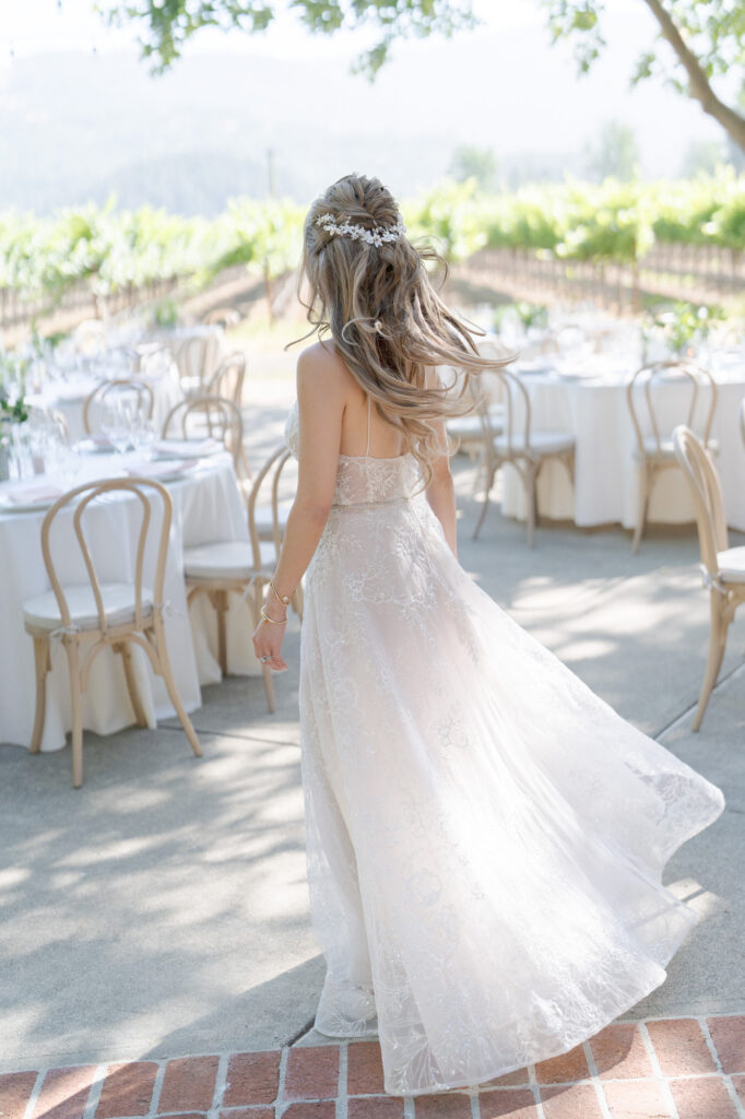 Beautiful bride in a white wedding gown stands in front of her wedding reception venue tables.