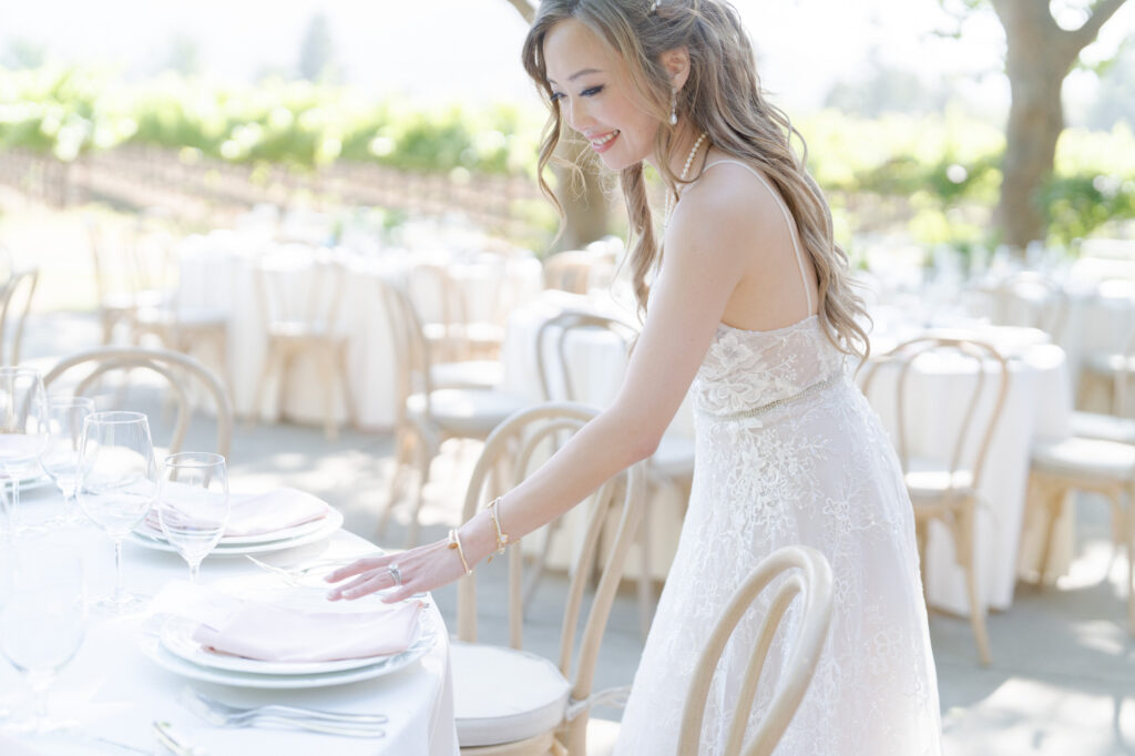 Bride arranges a plate on one of the tables of her wedding reception party venue.