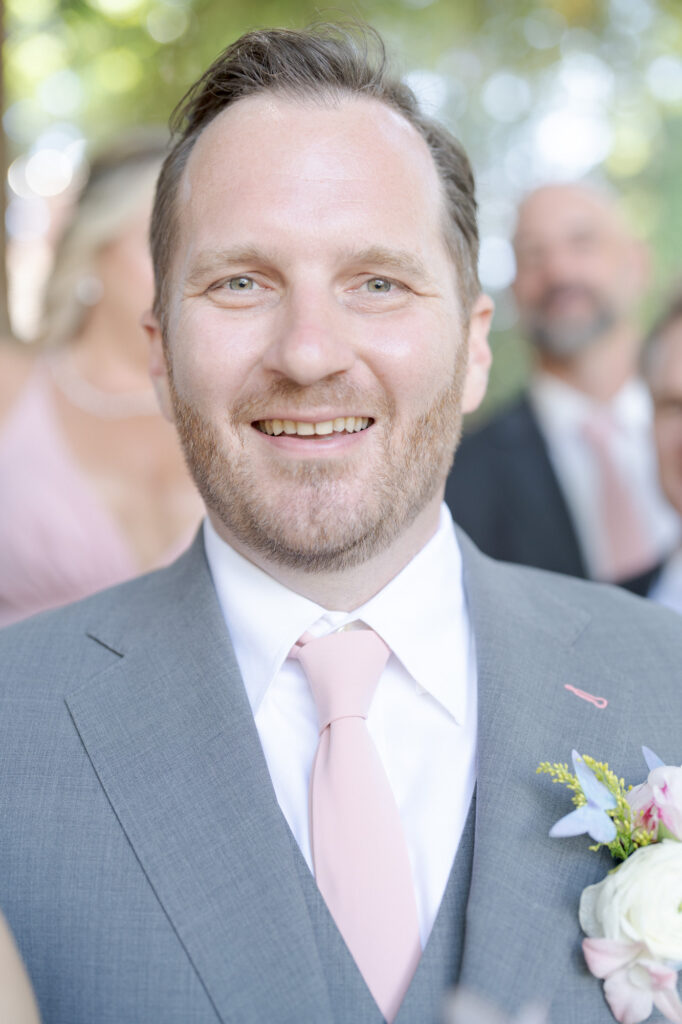 Elegantly dressed groom in his suit and pink tie.