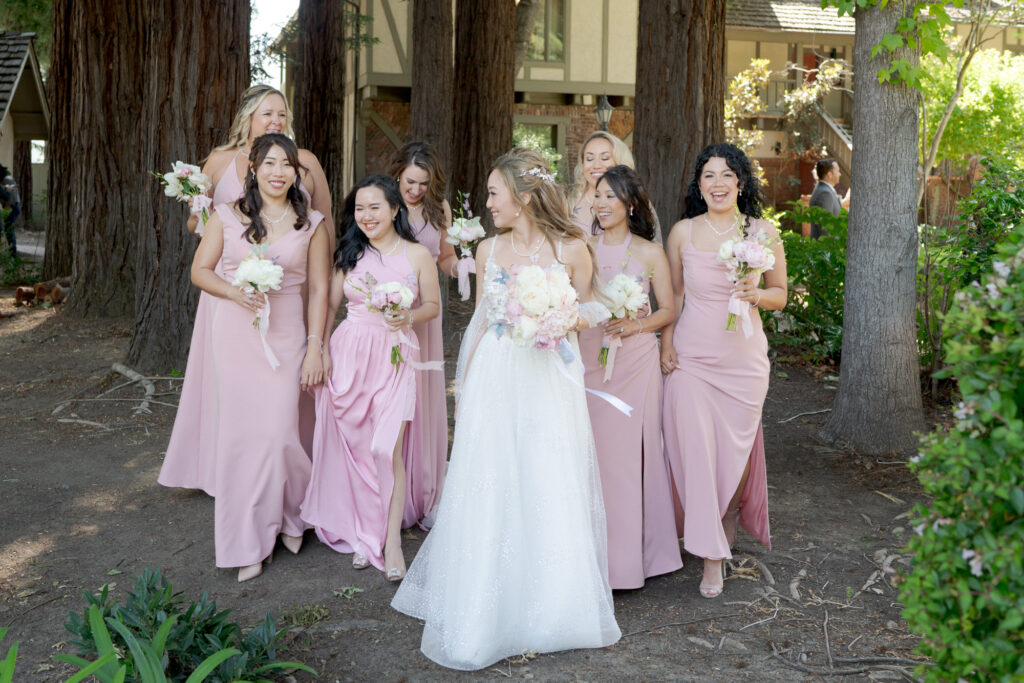 Bride and bridesmaids in wedding outfits hold bouquets of flowers.