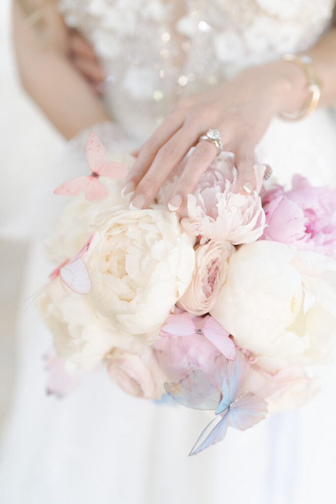 Bride with pretty nails and a ring on her finger holds a bouquet of flowers.