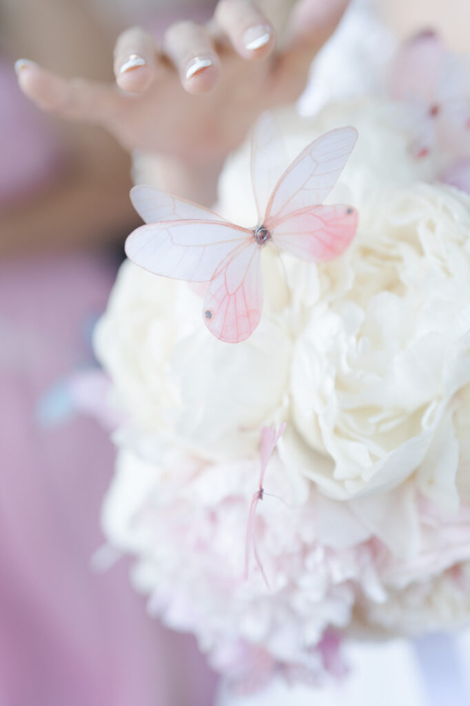 Bride with pretty nails holds a bouquet of white and pink flowers.