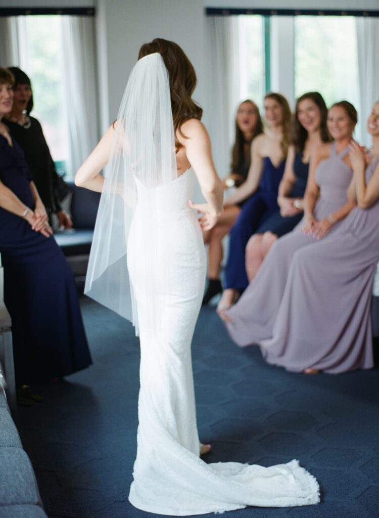 Bride in showcases her elegant wedding gown to her bridesmaids.