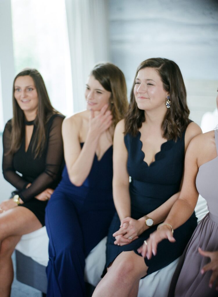 Pretty bridesmaids in blue gowns sit in a row.