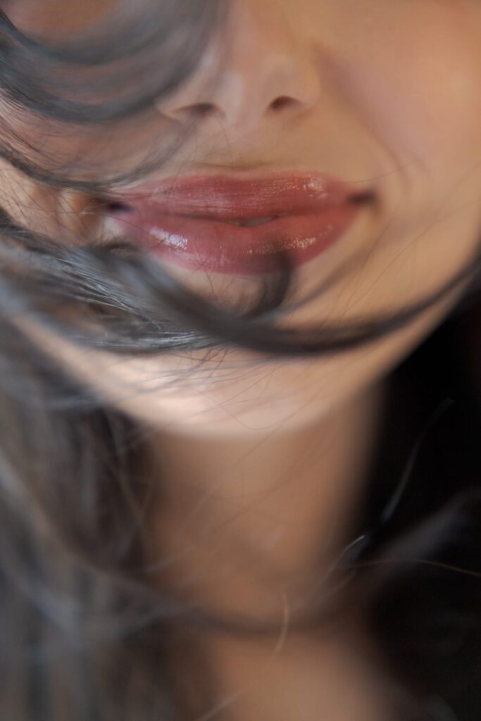 Close-up of a lady's face that shows her pretty lips and strands of hair coming on her face.