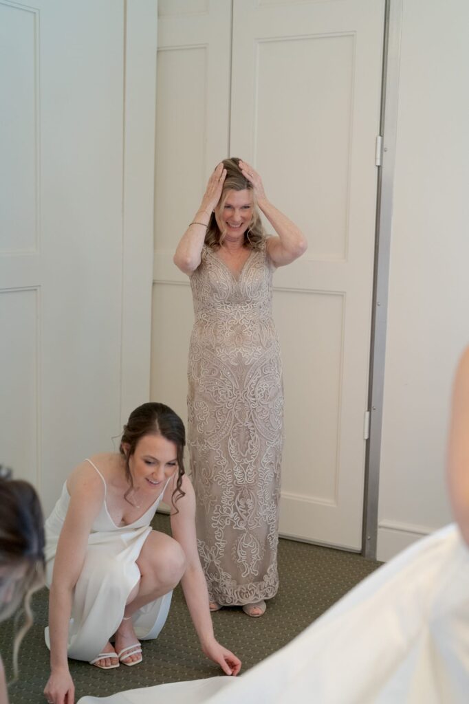 Bridesmaids and female guests help with the wedding gown.