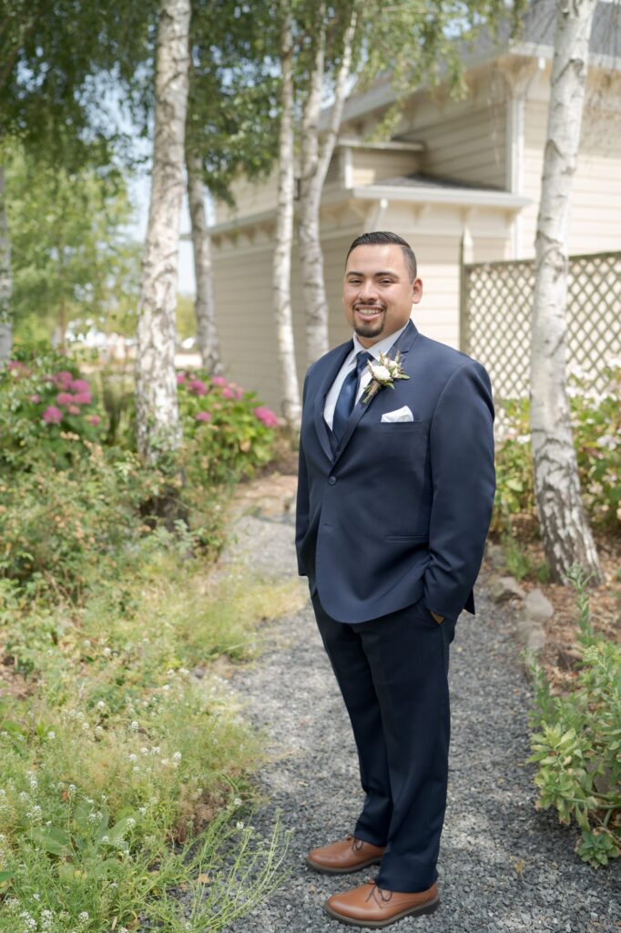 Elegantly dressed bridegroom portrait in a grassy garden.