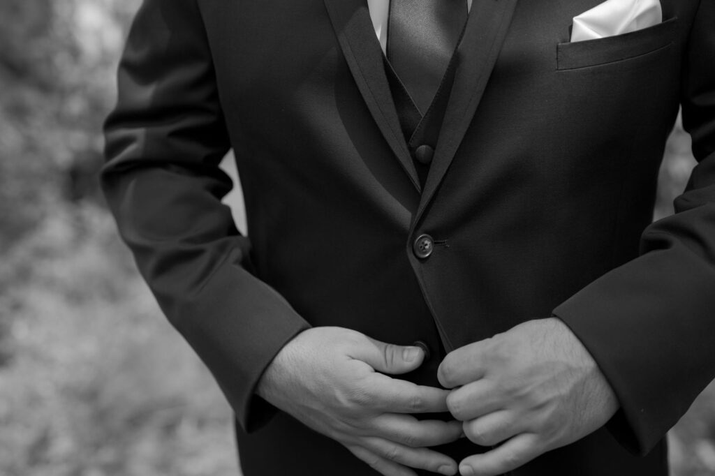 Man buttons his suit jacket.