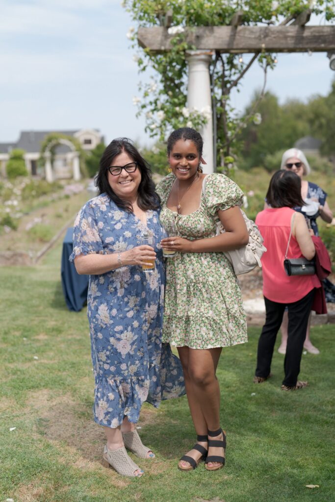 Two female wedding guests stick together and enjoy refreshment drinks.