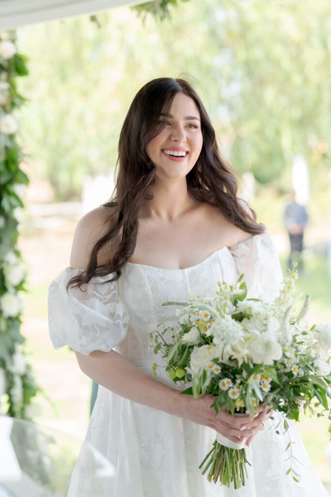 Beautiful wedding bride holds a bouquet of white flowers during her officiation ceremony.