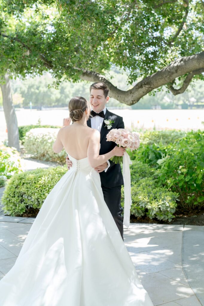 Groom holds his bride by her waist and pulls her closer.