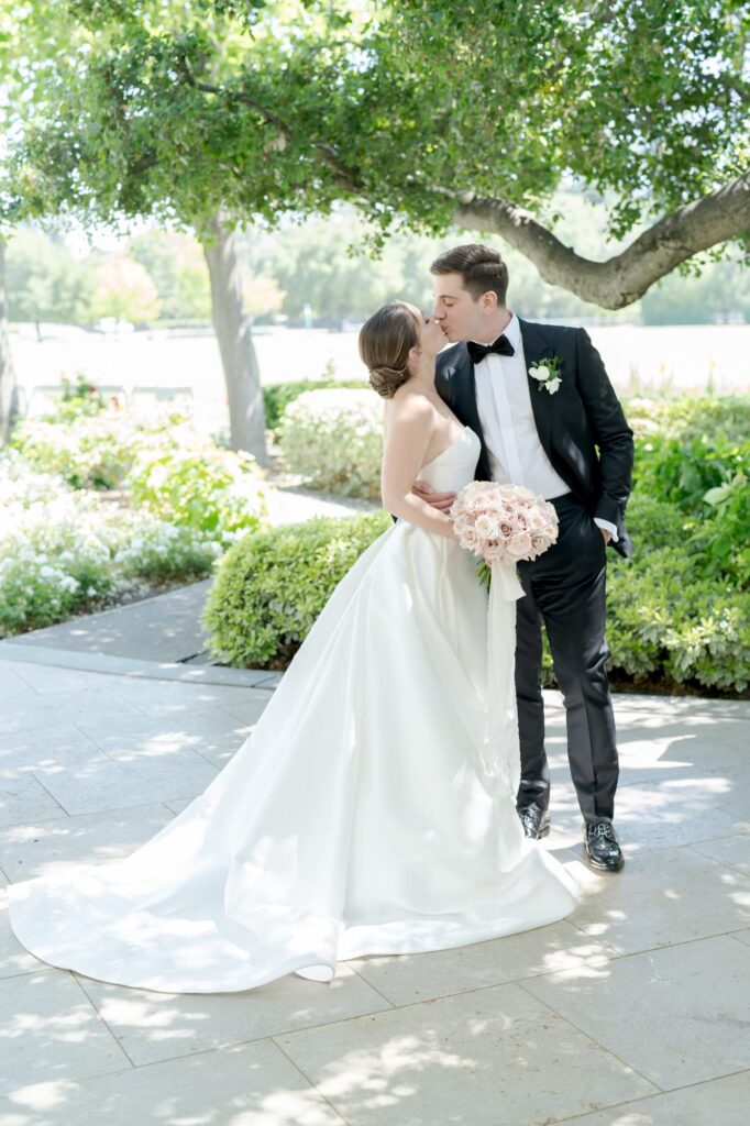 Picture-perfect snapshot of a bride and groom learning towards each other during a kiss.