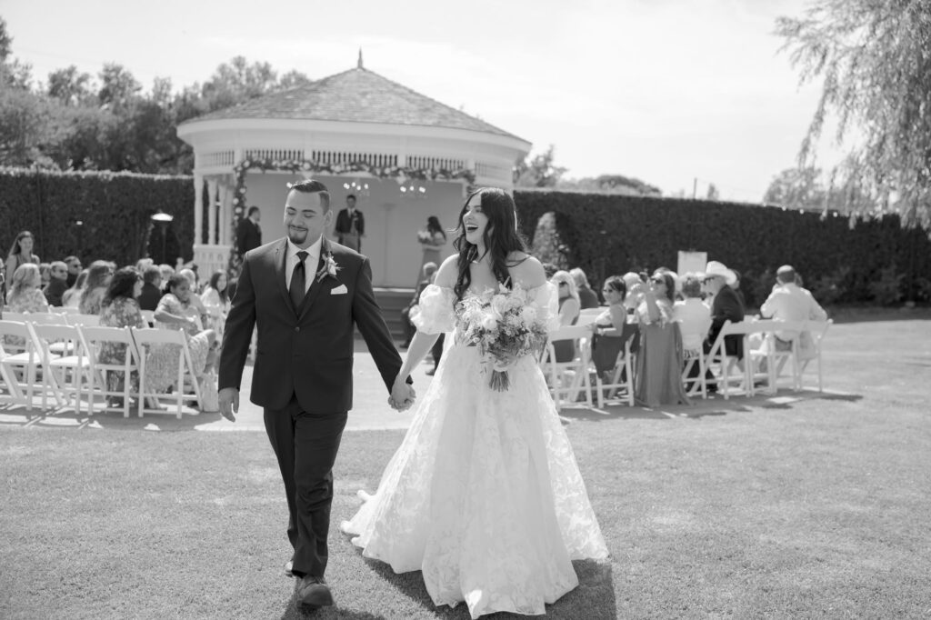 Wedding guests watch the newly-officiated bride and groom walk back up the aisle.