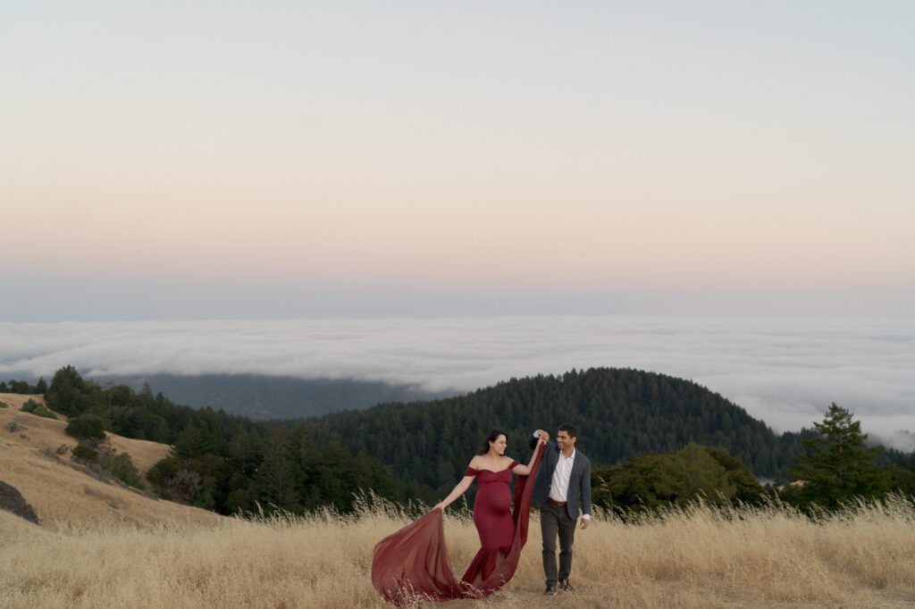 Husband holds his wife's hands for a cute twirl at a mountaintop.