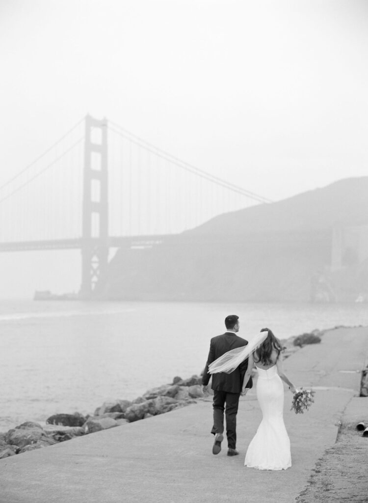 Editorial-style photoshoot of a newly married couple in wedding attire infront of the Golden Gate Bridge.