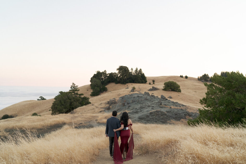 Husband and wife hold each other by the waist and walk the narrow path in Mt. Tam.