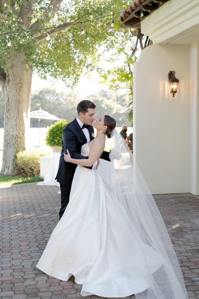 Groom holds his newly-pronounced wife by the waist and goes for a dipping kiss.