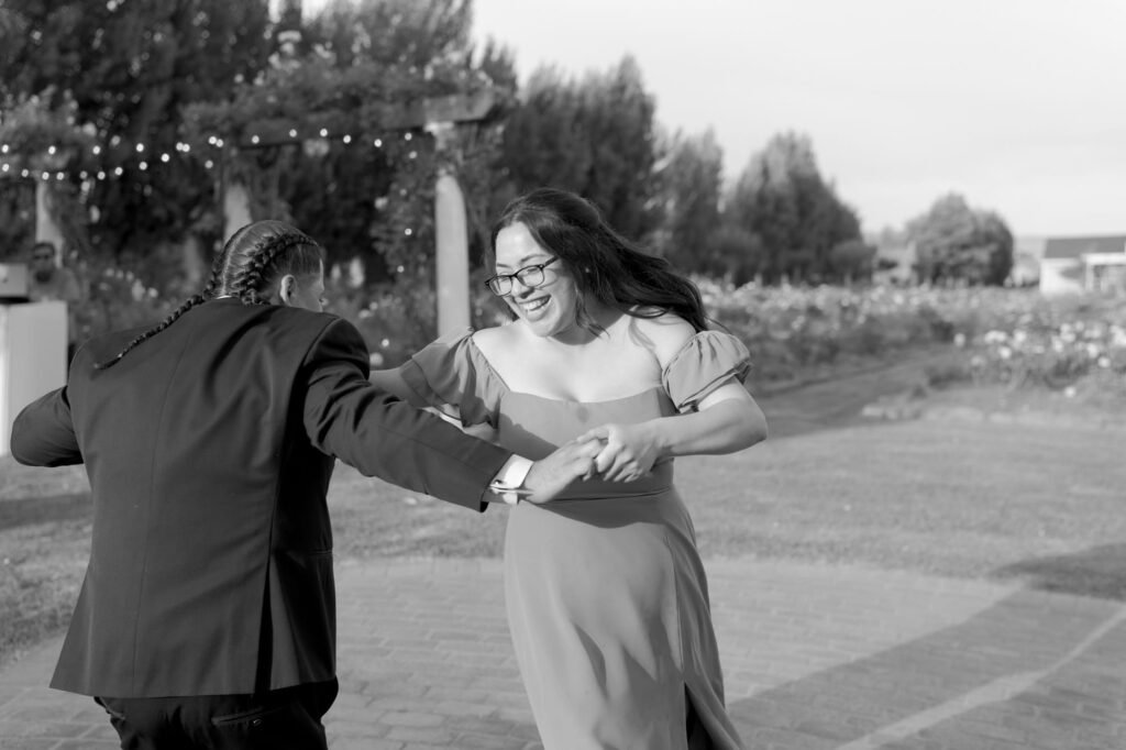 Female wedding guests hold hands and dance at the reception, going round each other.