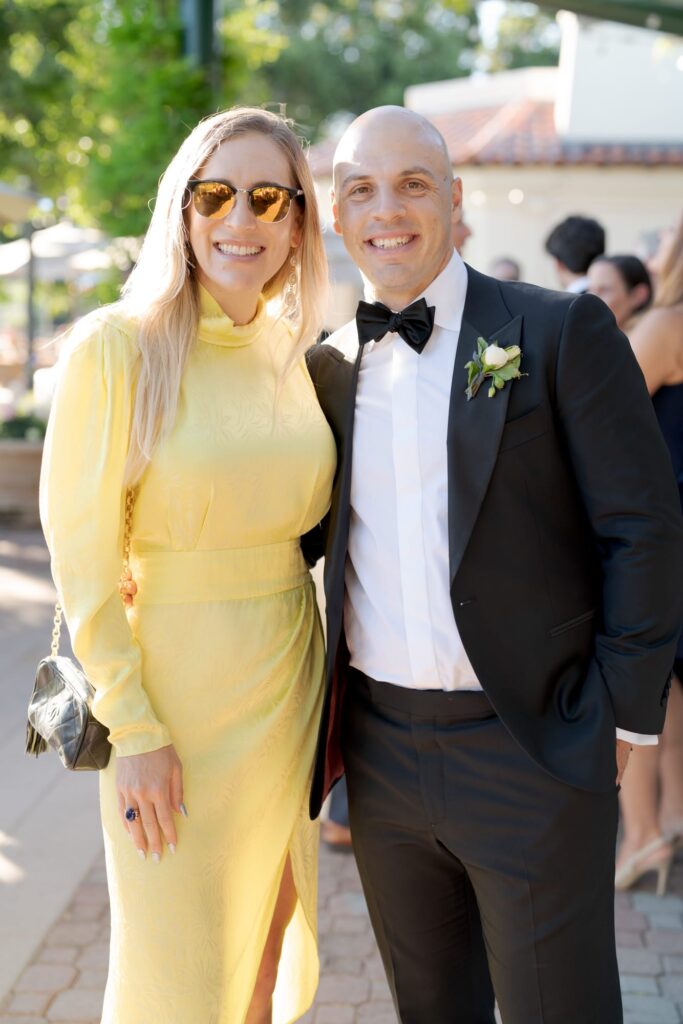 Wedding guest in yellow clicks a picture with a best man.