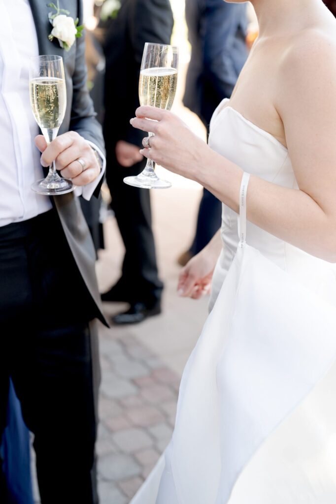 Bubbly champagne poured into glasses carried by the hands of wedding guests.