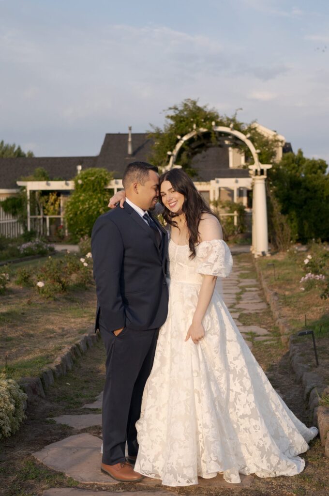 Bride wraps her hand around her husband's neck while the groom leans into her.