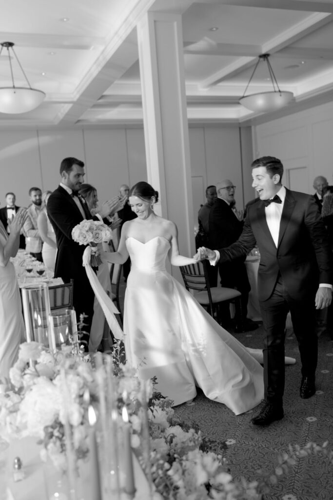 Groom and bride walks into the reception party venue in front of elated wedding guests.