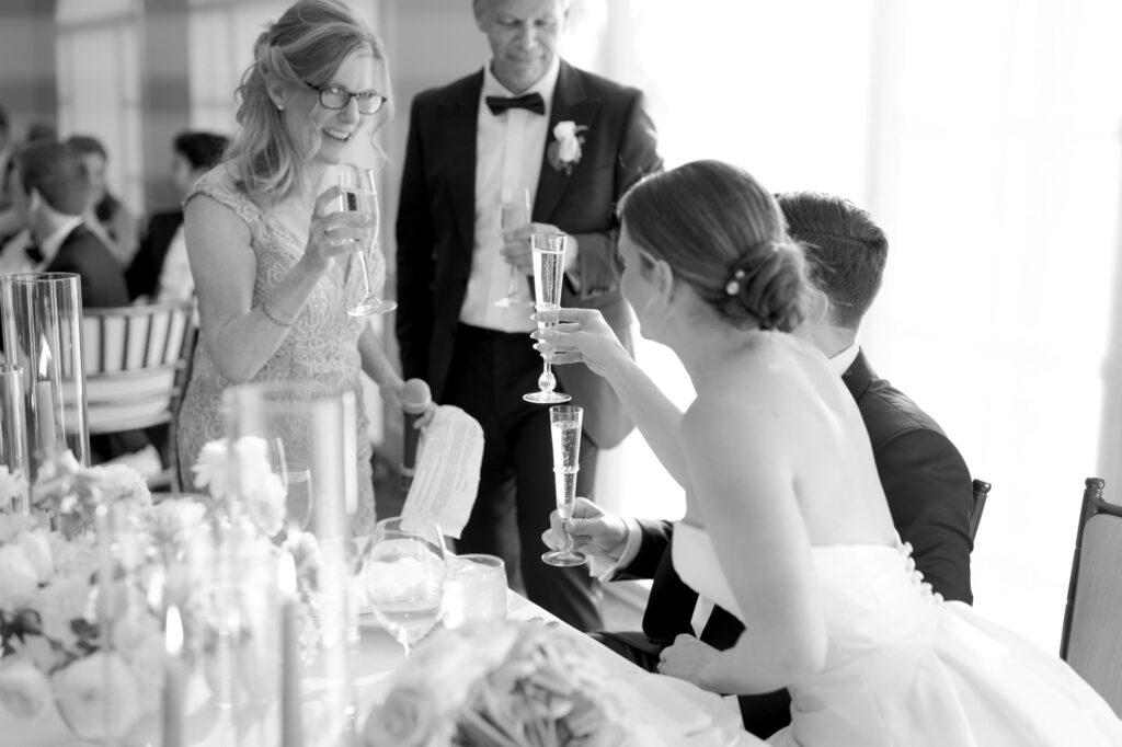 Wedding guests and the newlyweds touch their glasses for a toast.