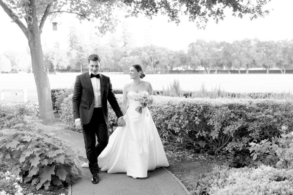 Bride and groom hold hands and walk in the Menlo Circus Club garden.