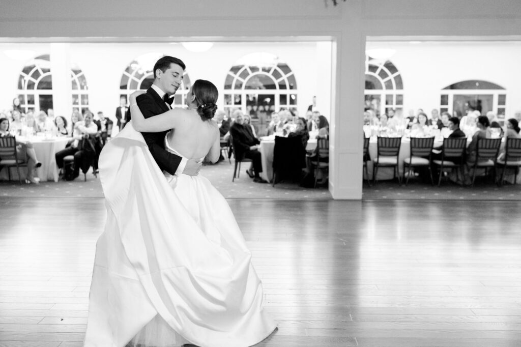 Newly-officiated bride and groom hug each other and dance at their reception party.