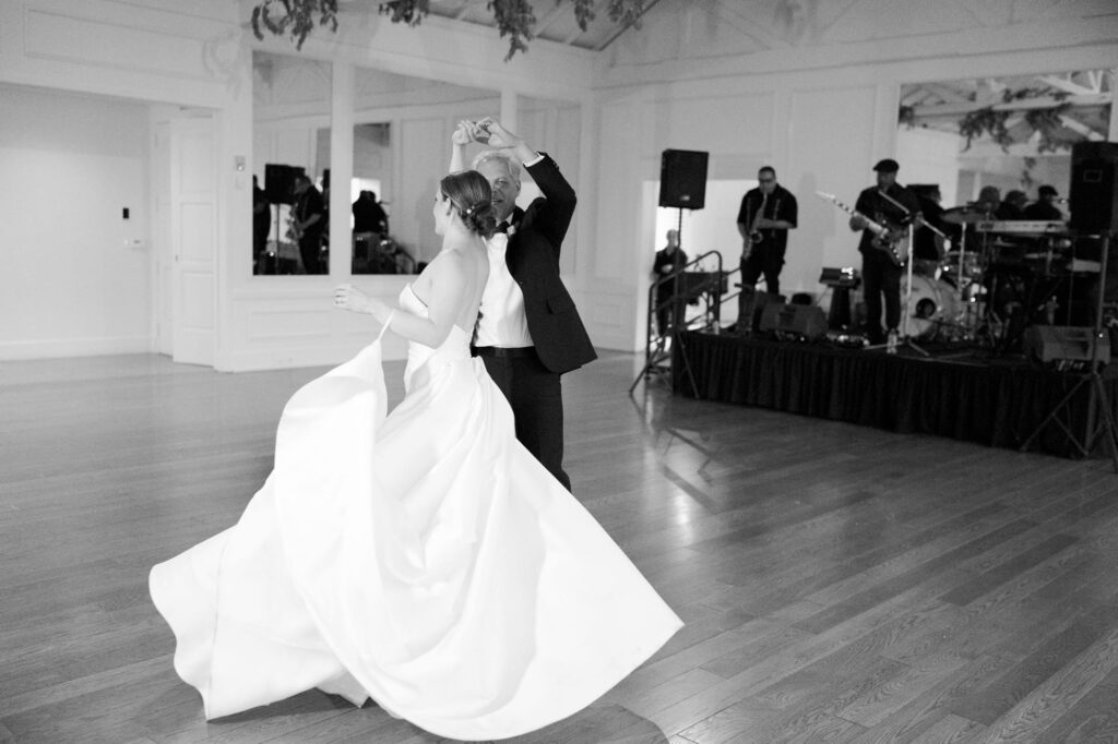 Bride dances with an older gentleman while live musicians play in the background.