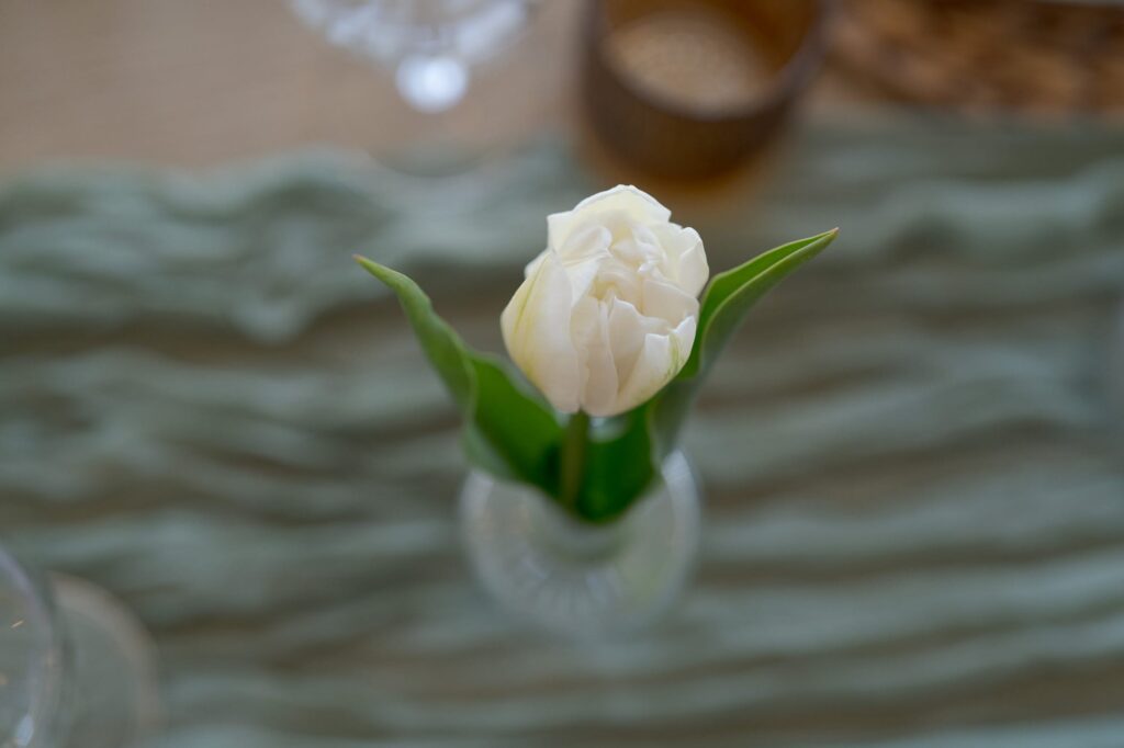 White flower with leaves on a glass vase.