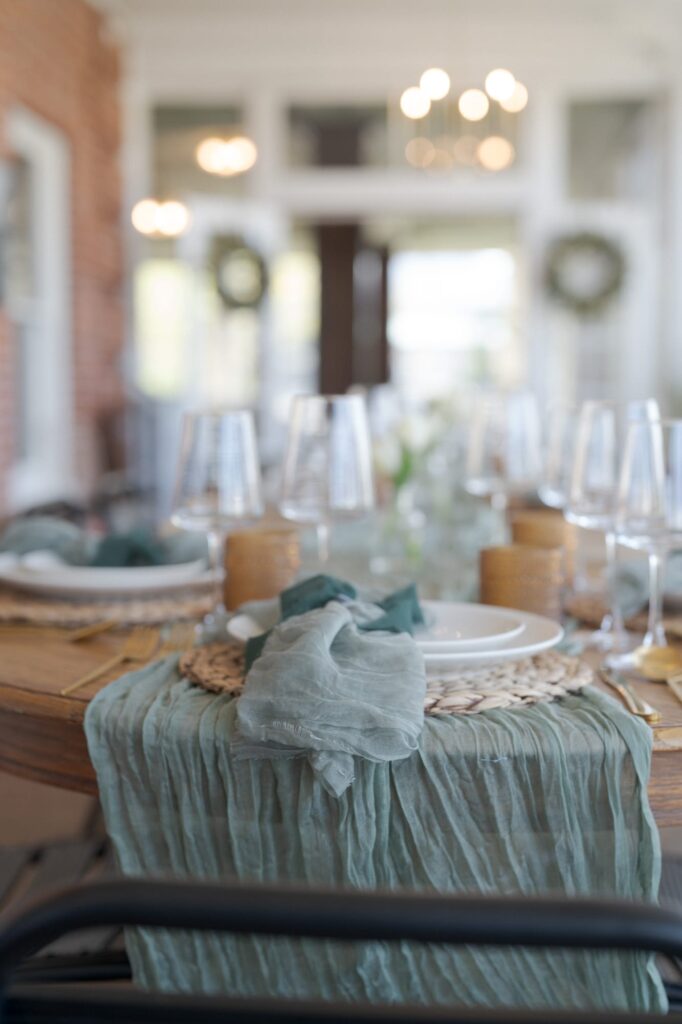 Wine glasses, plates, and placemats on a round wooden table.