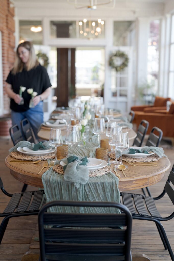 Lady arranges the table at Hot Lake Resort for a dinner party.