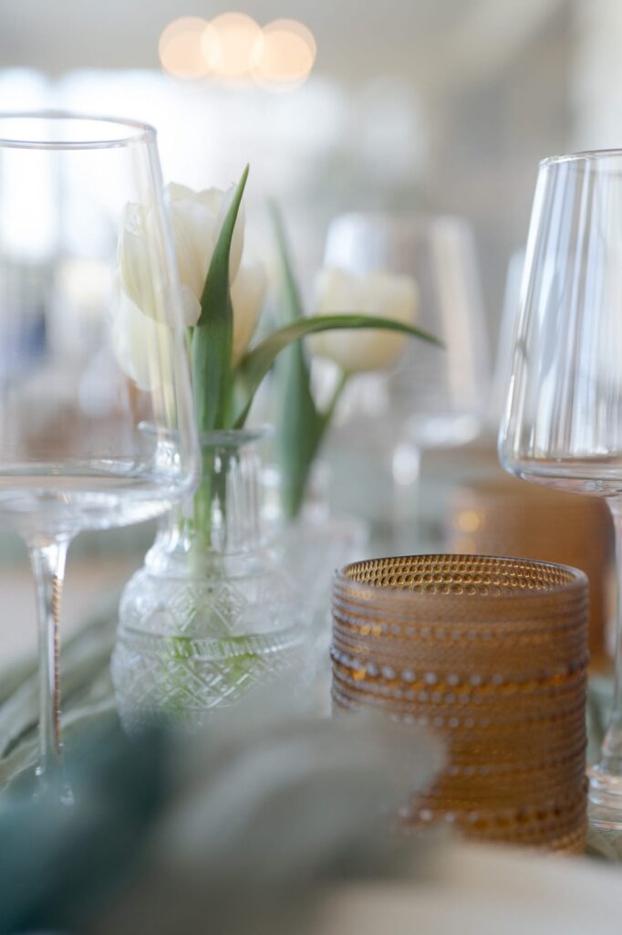 Aesthetic wine glasses besides pretty white flower centerpieces.