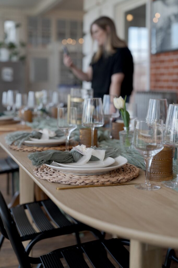 Artistic decoration of the dining table with cutlery, wine glasses, and white flowers.